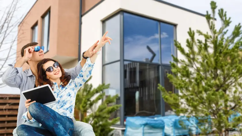 Smiling couple in front of their new home – Elegant Design Construction